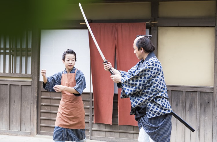 A martial arts teacher shows a student the proper way to wield a samurai katana sword.