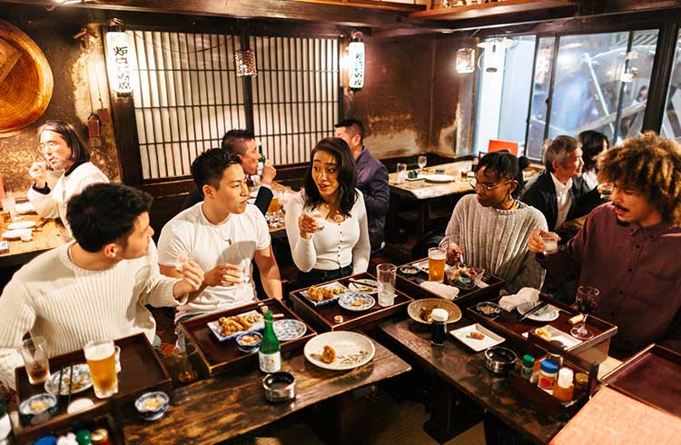 A group of travelers are enjoying food and drinks in a an Izakaya