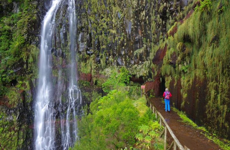 A hiker approaches Risco Waterfall on the island of Madeira.