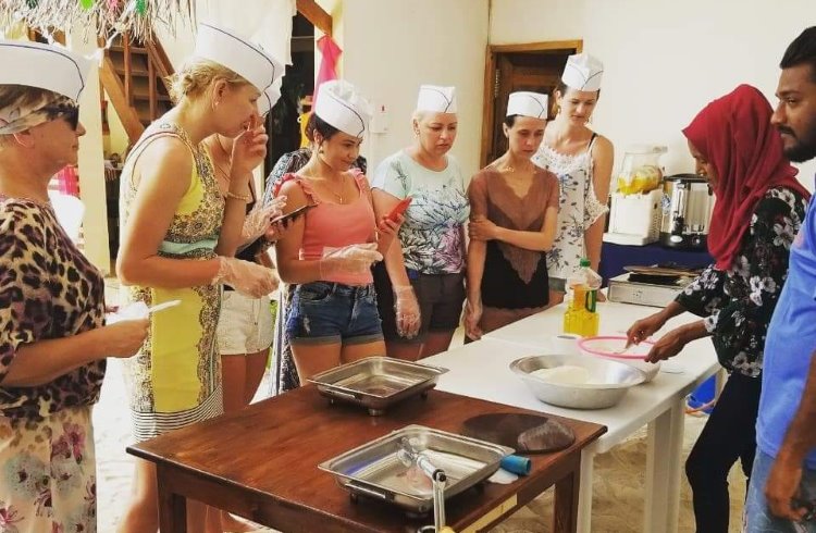 A group of women take a cooking class at a guest house in the Maldives.