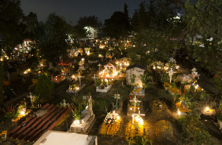 Graves decorated with candles and flowers in a cemetery in Mexico City.