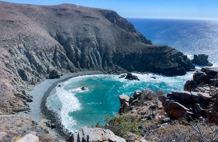 Clifftop view of a rocky cove and deep blue water near Todos Santos, Mexico.