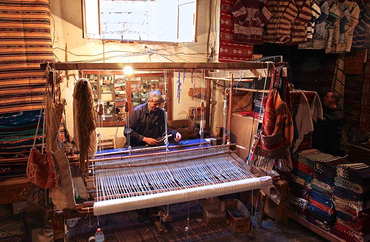 A Moroccan carpet being woven on a loom.