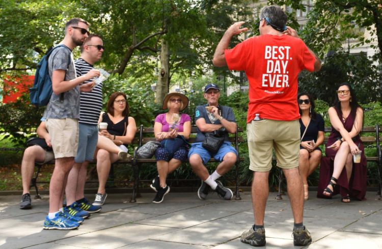 A group of visitors listens intently to a guide on a walking tour of New York's Lower East Side.