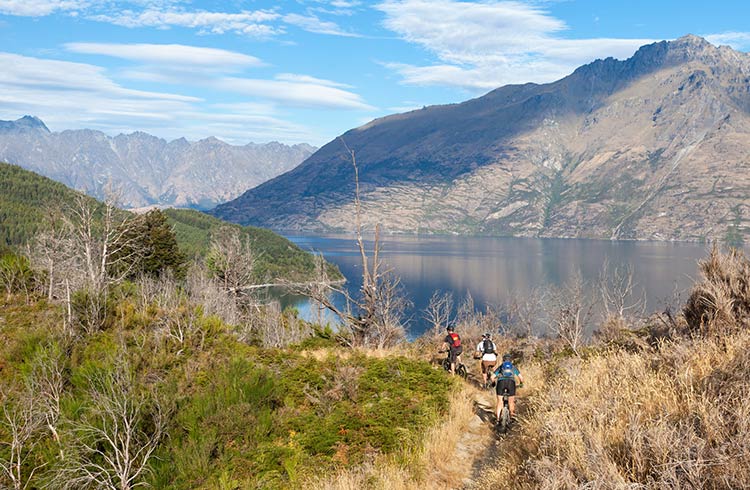 Mountain bikers cycling in Queenstown on the Moonlight Track looking over Lake Wakatipu