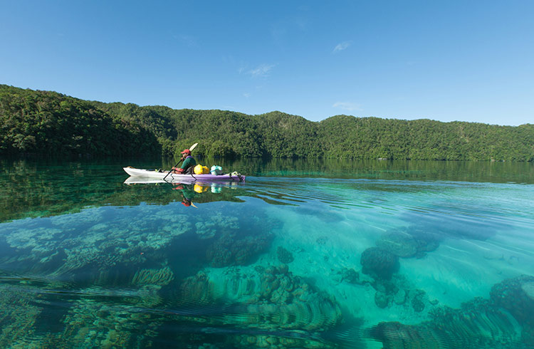 Kayaking on clear tropical water of a rock island lagoon, Nikko Bay, Palau