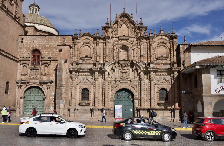 Taxis drive in front of the cathedral on the Plaza de Armas, Cusco, Peru.