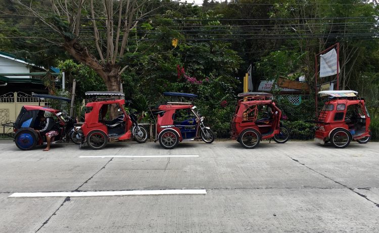 A row of tricycle taxis parked along a street in the Philippines.