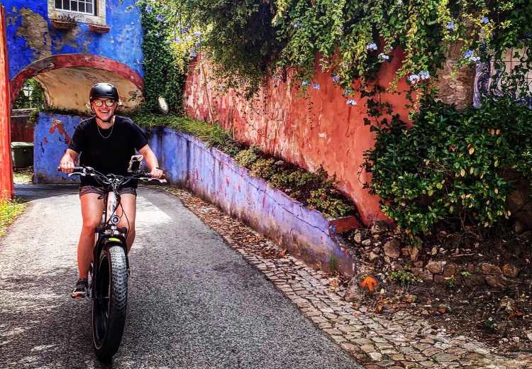A woman rides an e-bike up steep hill in Sintra, near Lisbon, Portugal.