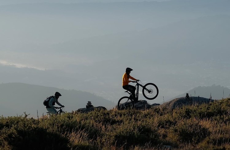 Two cyclists ride mountain bikes on the top of a hill in Viano do Castelo, Portual.