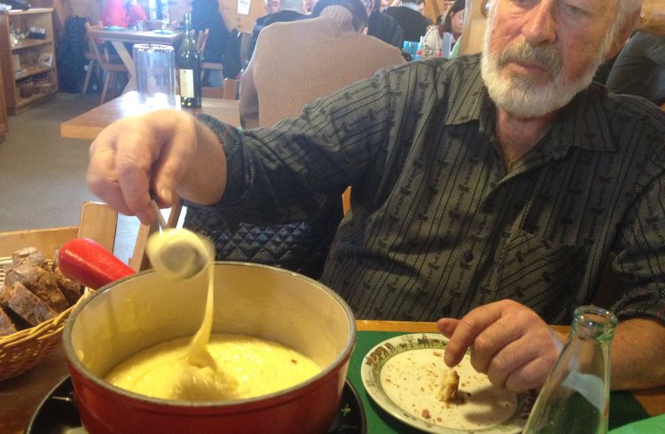 A man twirls Swiss fondue on a long fork.