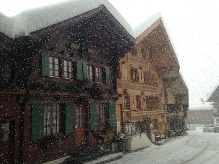 Snow falls in front of colorful chalets in the village of Rougemont, Switzerland.