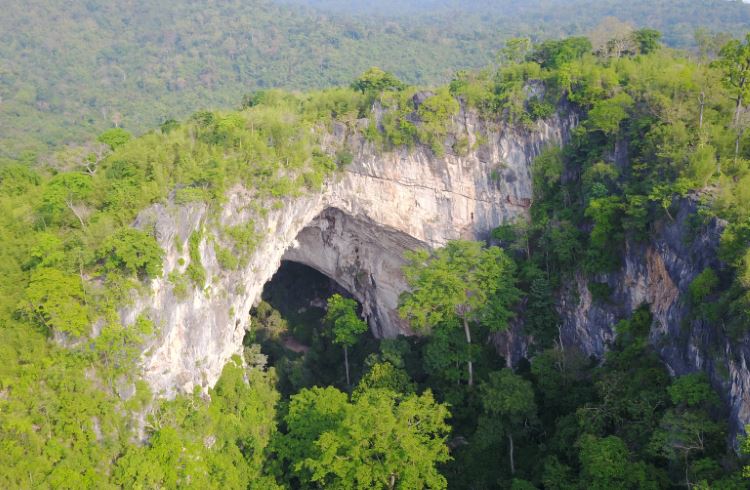 The 200-ft arch of Tarn Lod Yai cave rises above the jungle in Chaloem Rattanakosin National Park, Thailand.