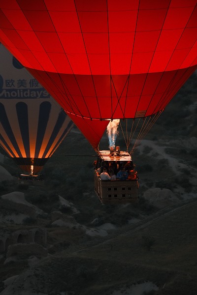 A close up of a hot air balloon basket in flight, at dawn