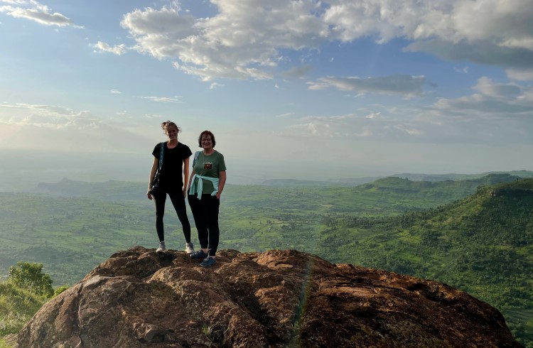 Two women stand on a cliff overlooking Elgon National Park, Sipi Falls, Uganda.