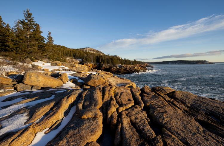 Snow-covered rocks on the shoreline of Acadia National Park in Maine.