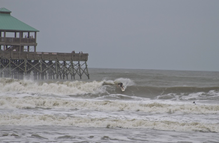 A surfer braves the stormy waves at Folly Beach, South Carolina.
