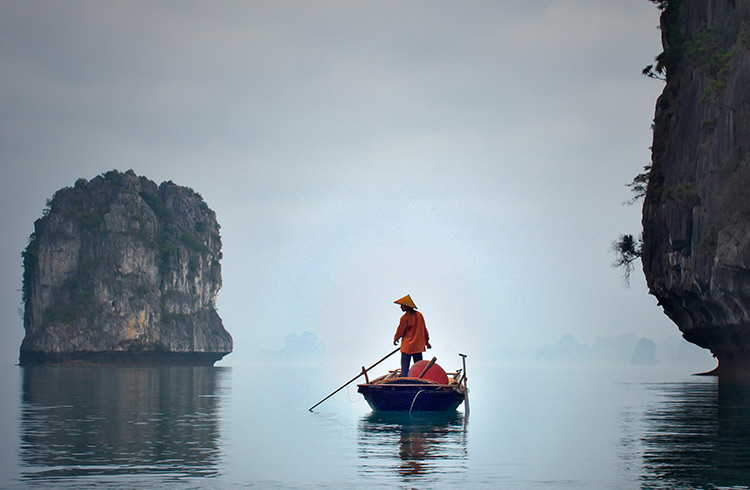 A fisherman paddling in Halong Bay.