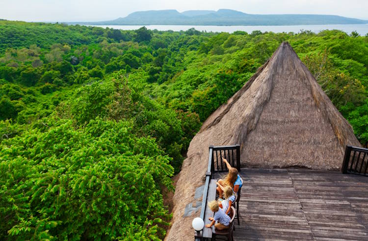A family sits on an elevated deck overlooking West Bali National Park.