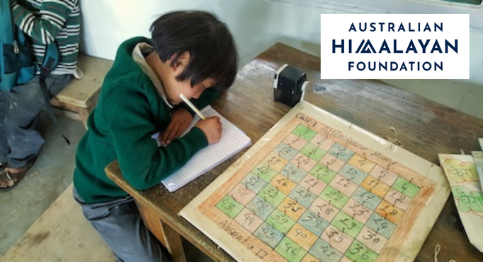 An image of a child in school writing in a school book and the Australian Himalayan Foundation logo