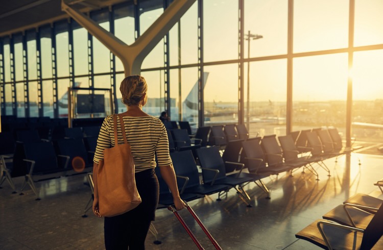 Shot of a young woman walking with her luggage through the departure lounge of an airport