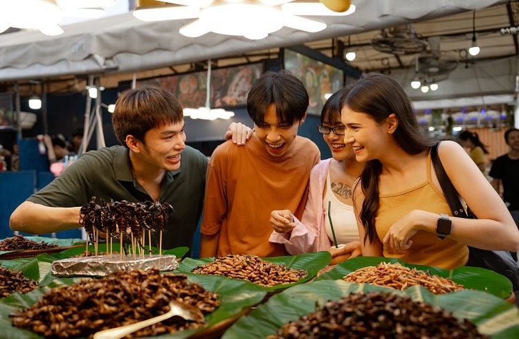 A group of young travellers eatig food at a street market