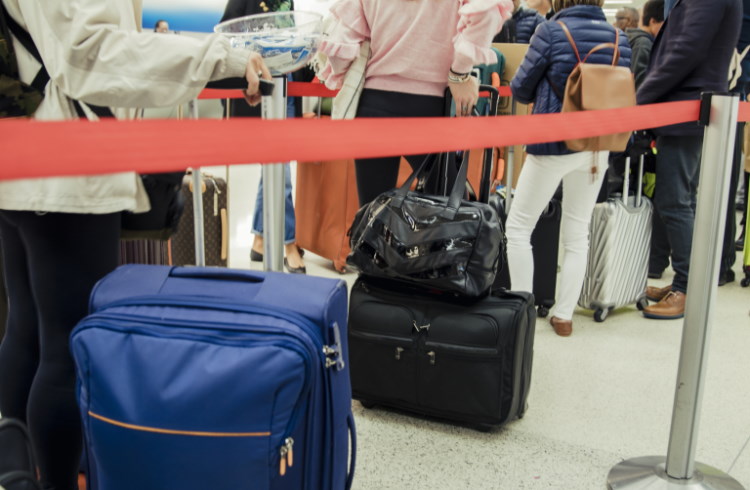 people lining up in a queue at the airport with their luggage