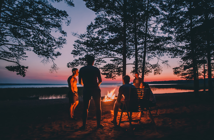 A group gather around a campfire at sunset