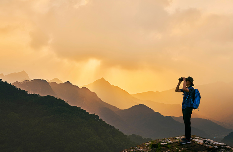 Man in mountains at sunset with binoculars