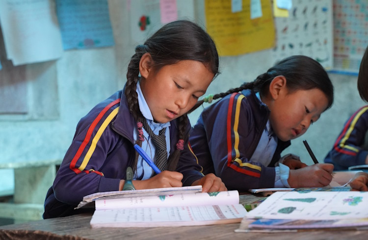 Children write in workbooks at a school in a remote Himalayan village.