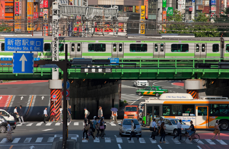 A Yamanote Line Train Crosses Over Pedestrians and Traffic at Shinjuku Station in Tokyo, Japan
