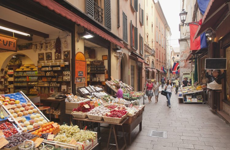 Shoppers stroll through an open-air food market in Bologna, Italy.