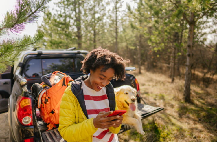 A woman checks her smartphone while camping in the wilderness.