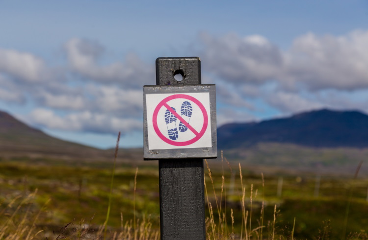 A sign in Iceland asking hikers not to stray off the path.