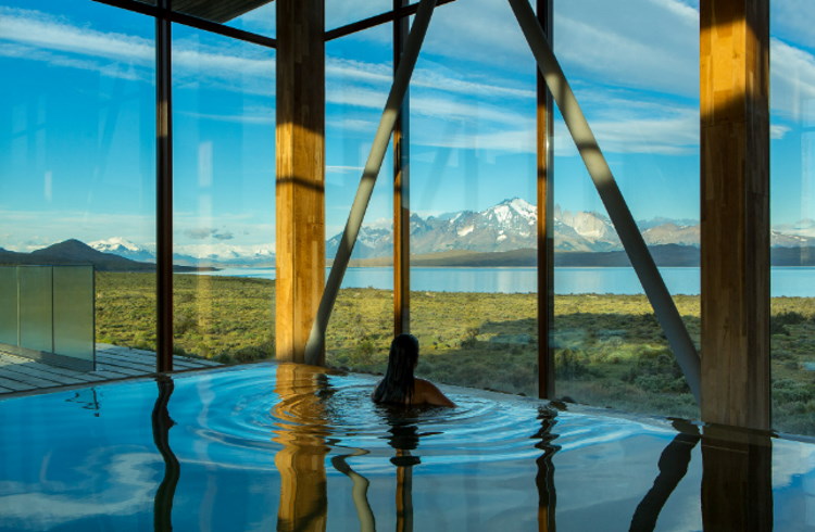 A woman gazes at the Andes mountains from an indoor spa pool in Chilean Patagonia.