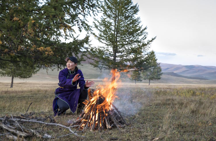 A female trip assistant lights a fire on a tour of Mongolia.