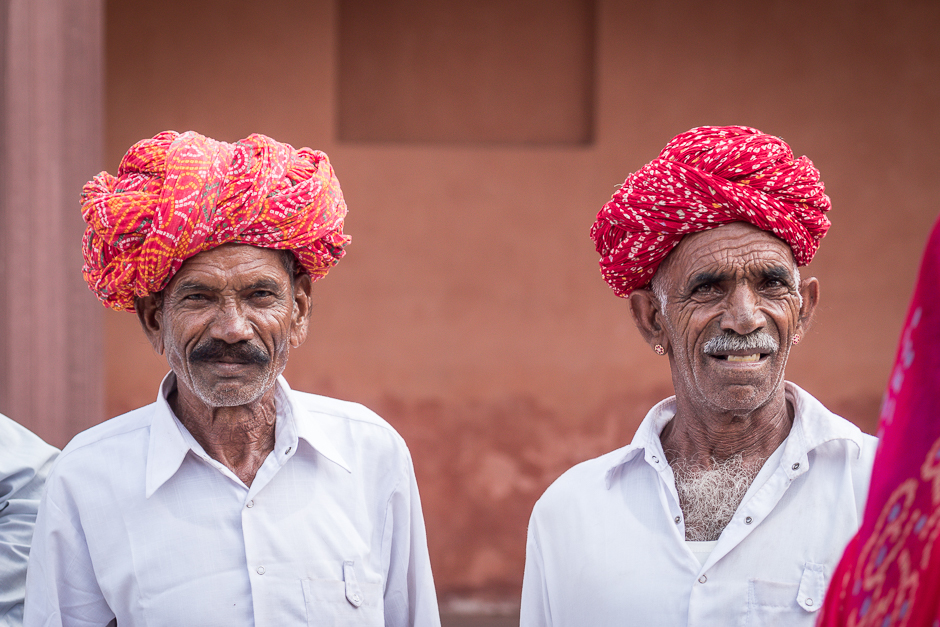 Two Gujarati farmers, dressed in neatly pressed white shirts and vibrant turbans. Quickly combing their moustache and assuming the strongest stance upon request to click a photo. 