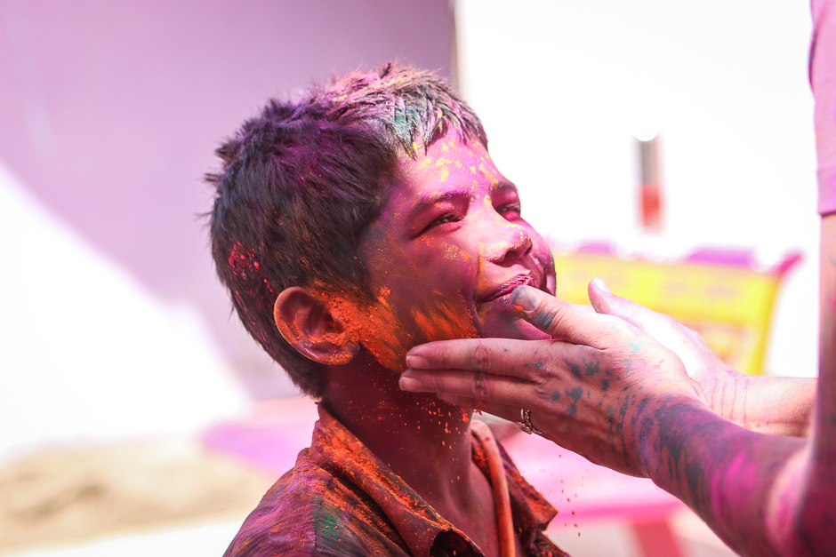 A young boy plays Holi with a foreigner during the popular festival, also known as the festival of colour. A time where everyone is vulnerable and everyone is open, young and old throw coloured powder and dance in the street. 