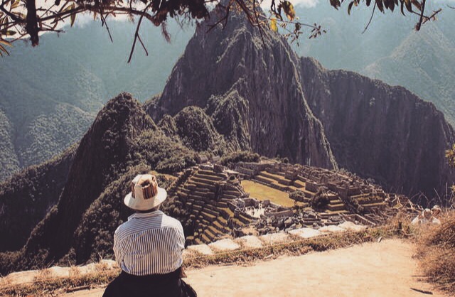 A man sits alone among the wonders of Machu Picchu. 