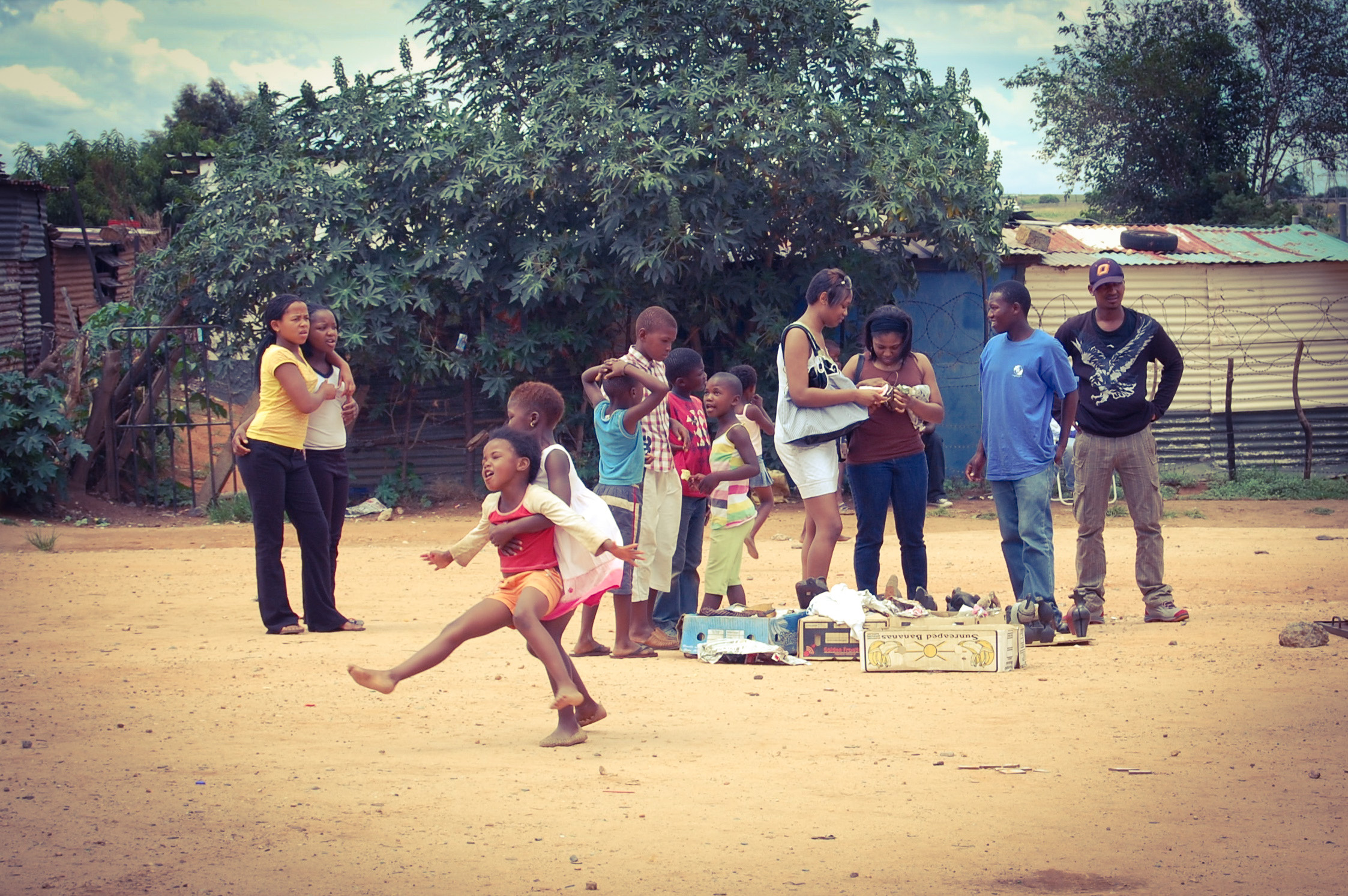 In Khayelitsha, children play while tourists look through their homemade gifts.