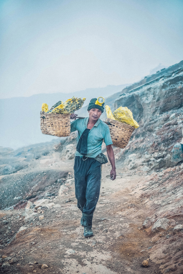 Kawah Ijen, East Java. Sulphur miner. Men here carry baskets of hardened yellow sulphur weighing 70 to 90kg up a steep rocky path from the crater floor around ten times a day.