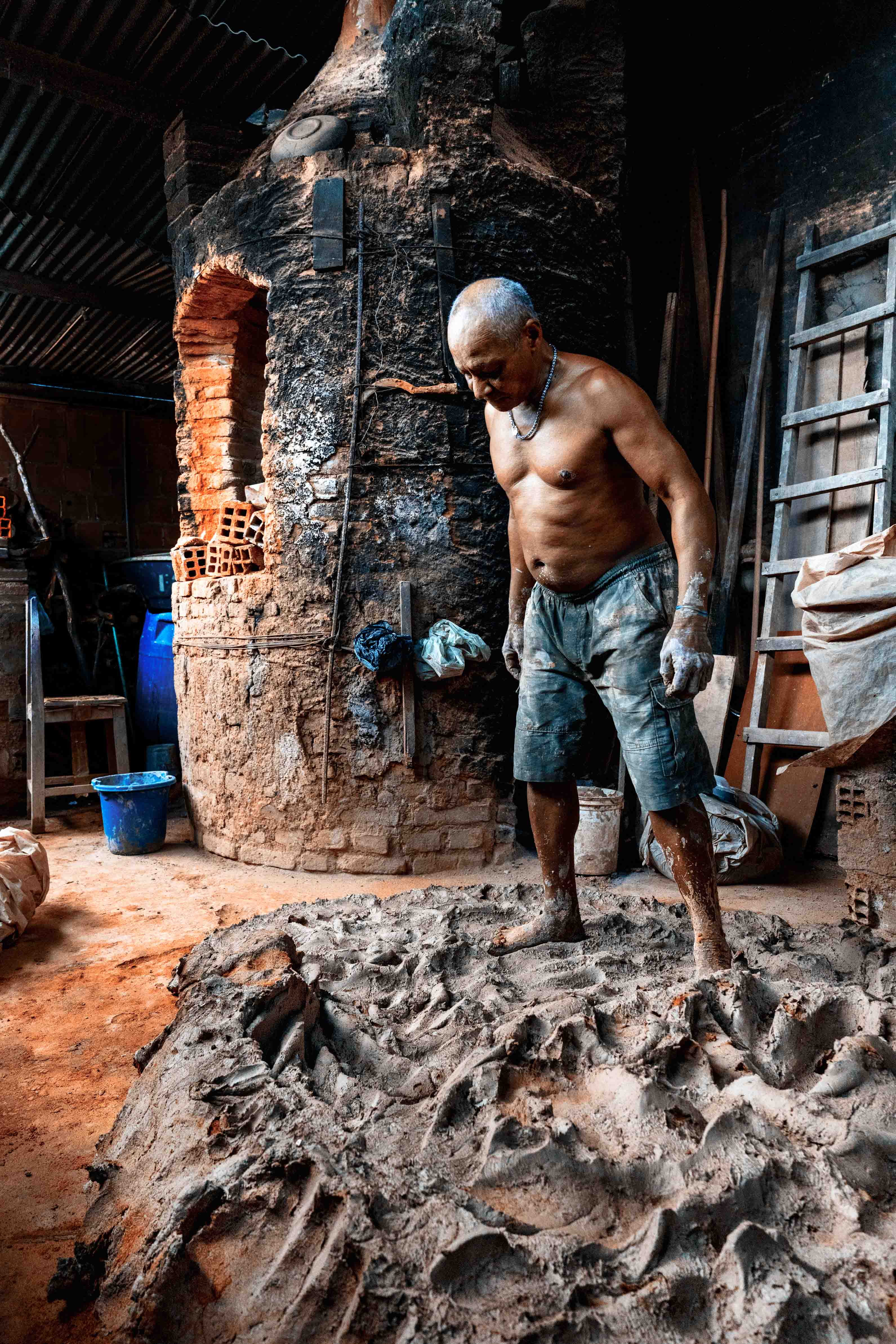 Tracunhaem is a city in northeastern Brazil, known for handicrafts with clay. For generations, potters have been working in their workshops, making their lives with clay. This is a view of one of these shops. (In this image: Sr. Rosimario treads the clay to remove impurities and prepares it to mold)