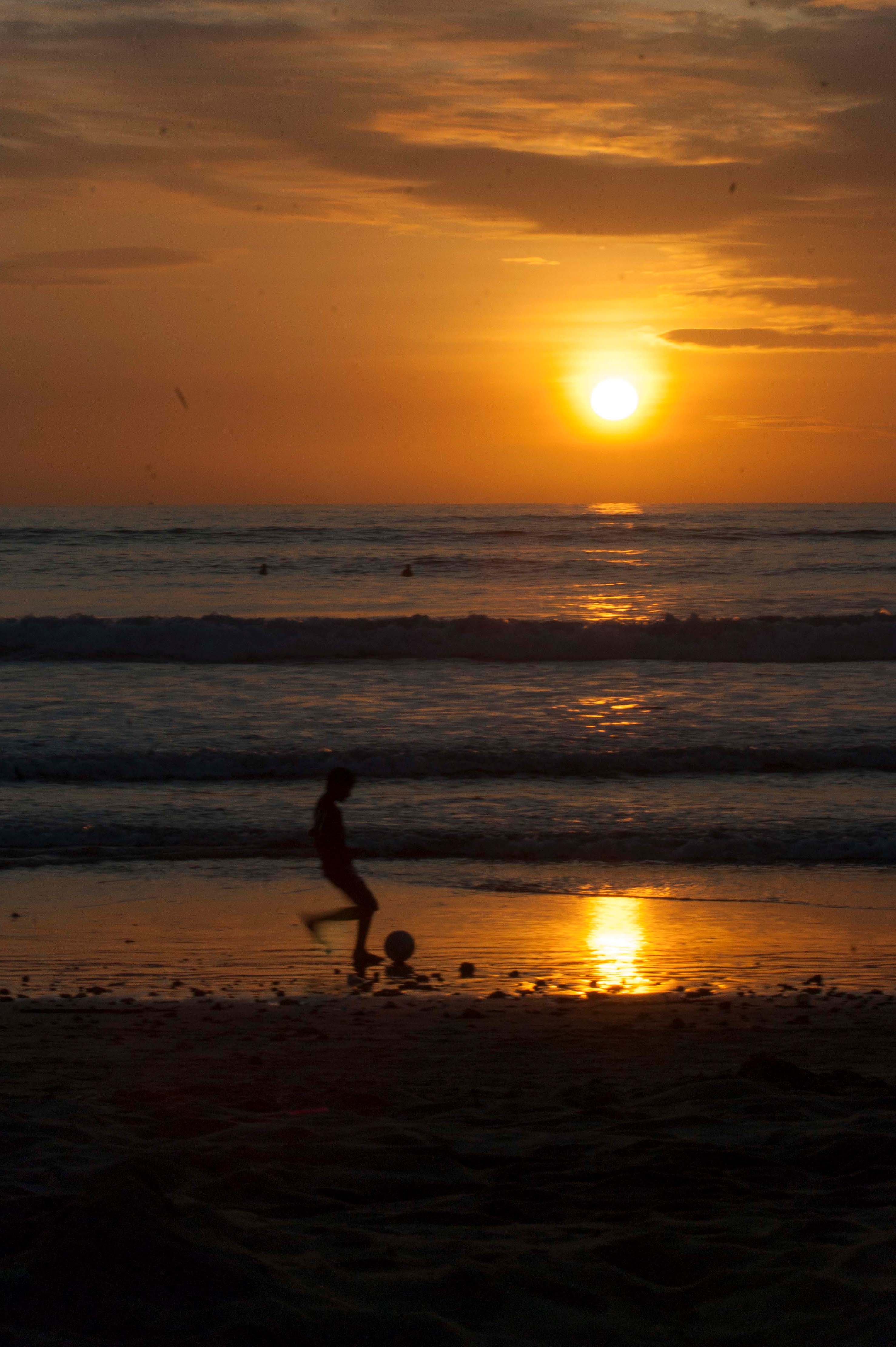 A boy kicking a soccer ball enjoying the sunset in Puerto Lopez