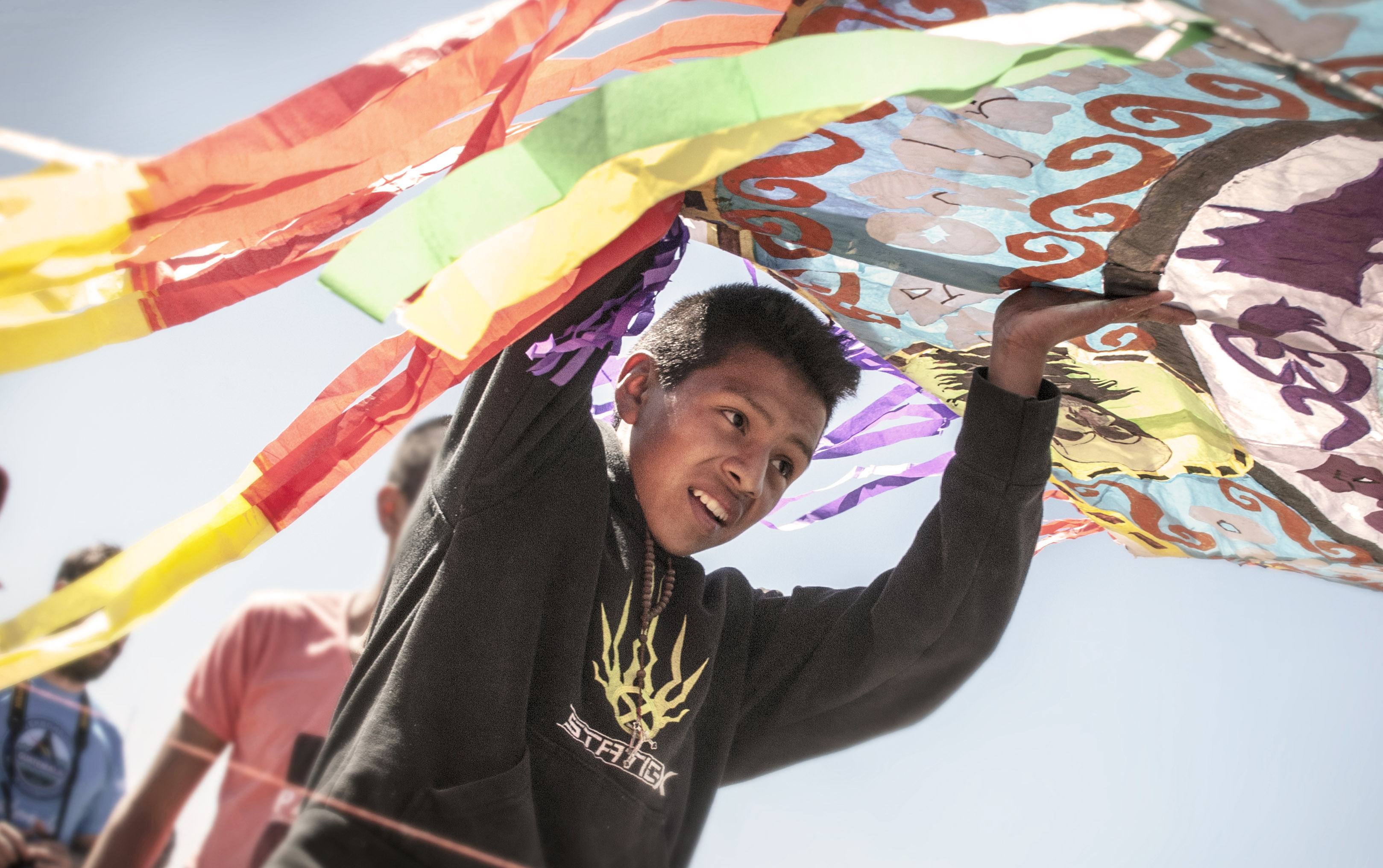 A young competitor rushes to return his fallen kite to the starting line for a second launch attempt.  The construction and flight of colorful kites has been in practice thousands of years, and was believed to be a way to communicate with the dead.  Today the flights also serve as a spirited competition for the areas' youth.