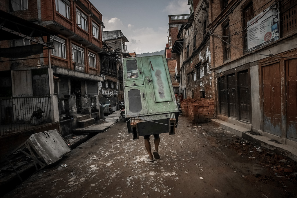 A man is carrying an almirah and leaving the city. Sankhu, Nepal. May 9, 2015