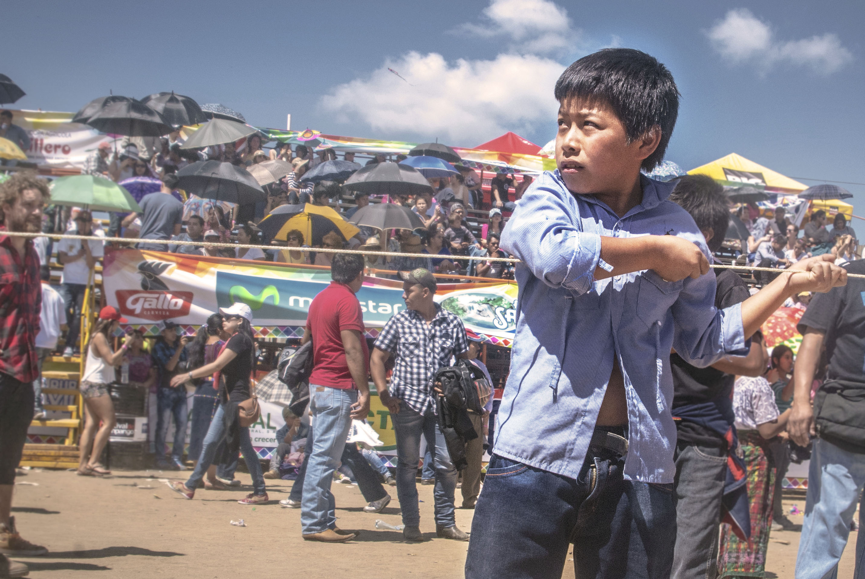 Kites are so large, they require teams of four or more children to break into the sky.  A young boy looks back to make sure his teammates are ready to run before giving the signal to launch.