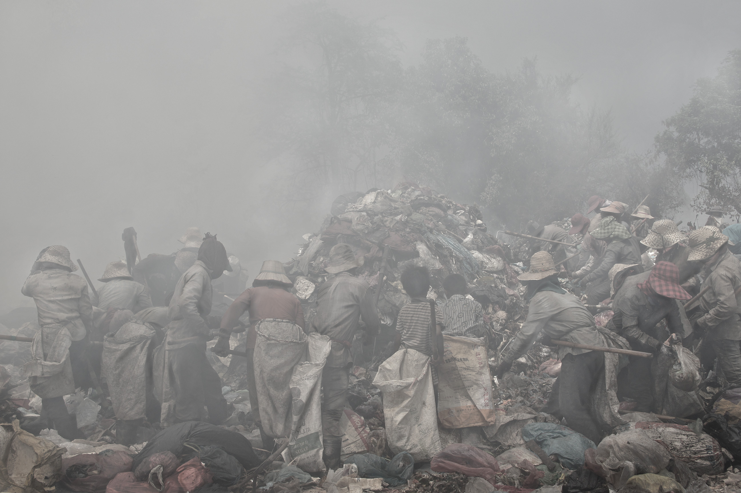 A truck drops a fresh load of waste and the frantic rush begins, as workers battle true the thick smoke to be the first to find the best recyclable items