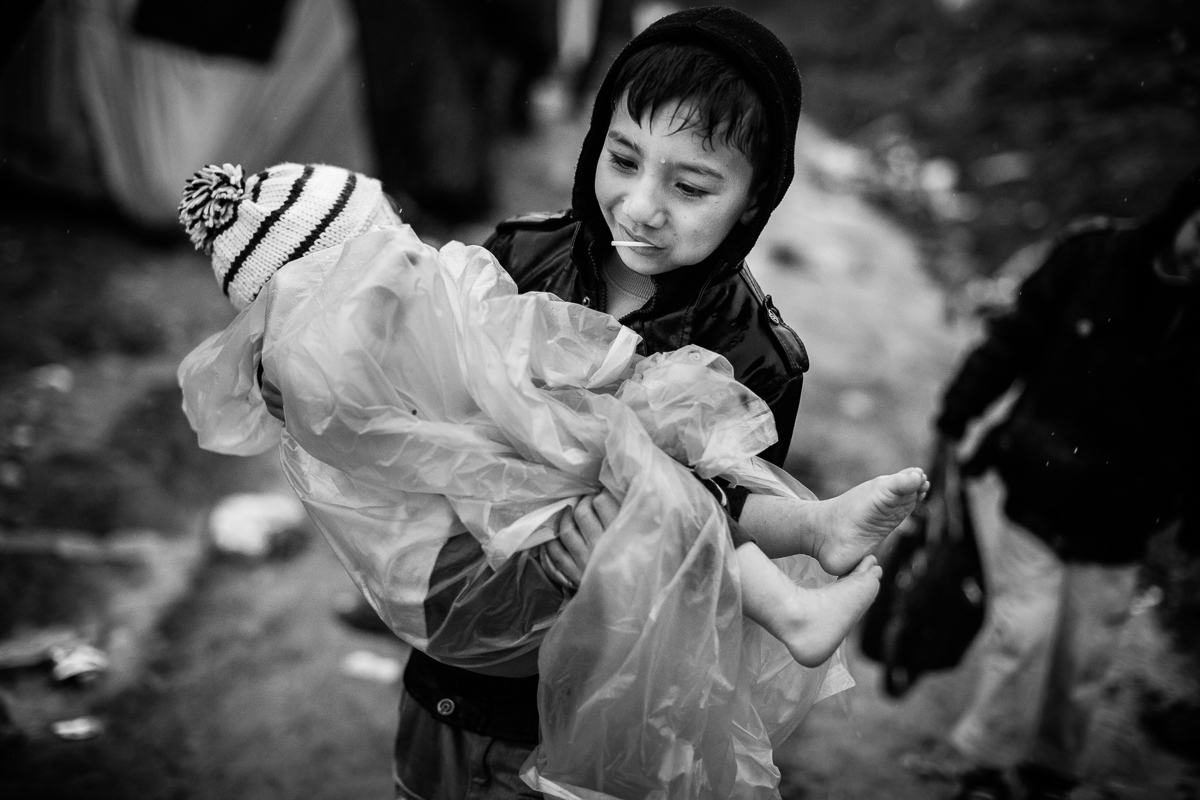 A boy carries his younger brother in the registration camp of Moria. Rain has been pouring down for many days and refugees, especially children, suffer a lot from it, barely having any protection at all.
