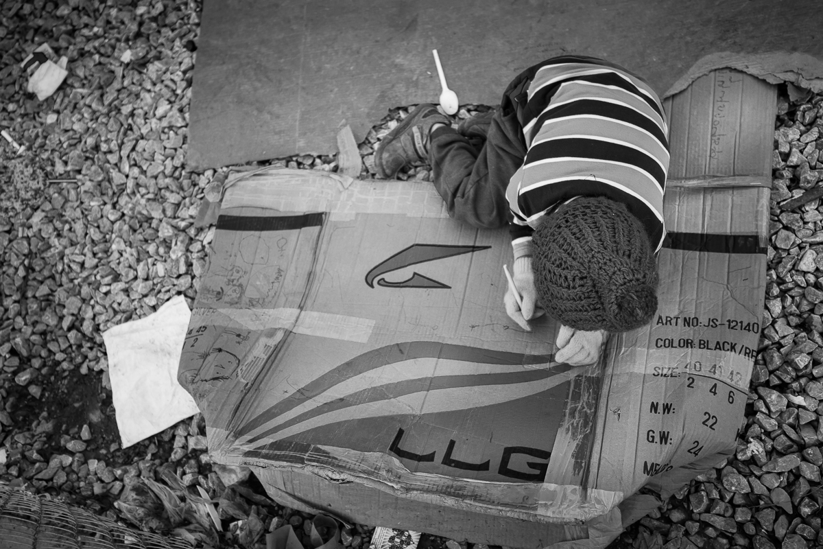Entertainment is sparse for children in refugee camps but they always find a creative way to get their minds off the hardships of their situation. Mostly smiling and playing with anything they find, children are an inspiration for courage as is this little girl drawing on a discarded cardboard box in the camp of Moria.