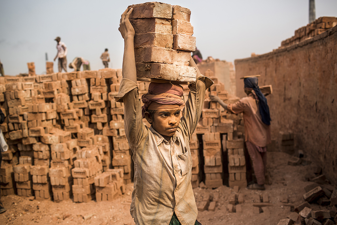 An underage boy works carrying bricks on his head in Ashulia area on the outskirts of Dhaka, Bangladesh. There are thousands of brick fields in Bangladesh where workers slog long hours to churn out millions of bricks to fuel a construction boom in the country. Dhaka has been named, according to several reports, the worst city in the world to live in.